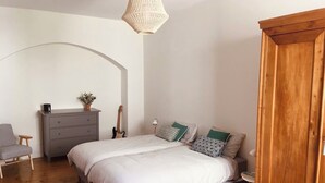 Een slaapkamer met een bed, een dressoir, een gitaar, een stoel en een kledingkast.