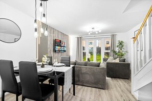 Ein modernes Wohnzimmer mit Essbereich, einem großen Fernseher und Blick ins Freie.