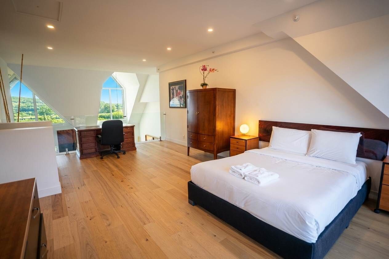 A bedroom with a bed, desk, and wardrobe.