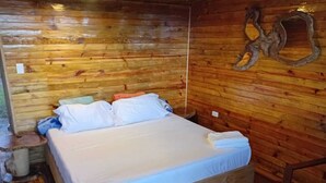 Una habitación de cabaña de madera con una cama, una mesita y un adorno en la pared.
