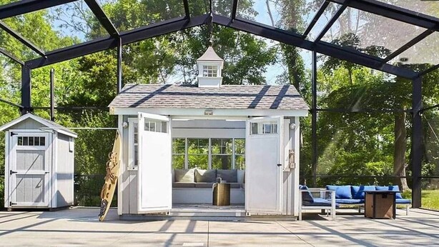 A covered pool area with a small gazebo, a shed, and a lounge chair.