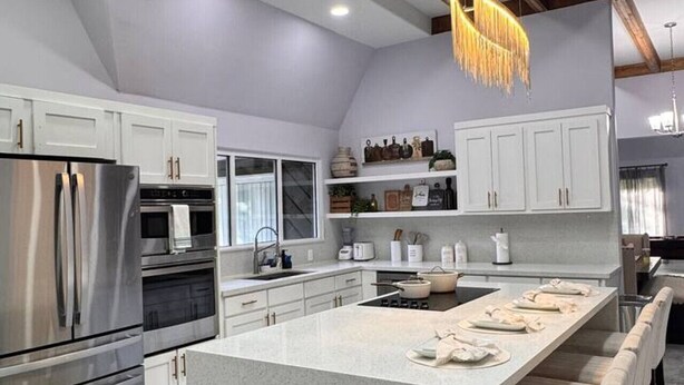 Een moderne keuken met een centraal eiland, roestvrijstalen apparatuur en een hanglamp.