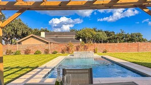 Een zwembadgedeelte met een pergola, een jacuzzi en een tafel met snacks en drankjes.
