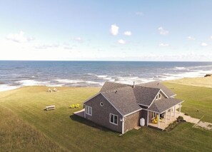 A house with a large lawn and a view of the ocean. - Ocean Front Cottage With Panoramic Water Views- Seconds To Cousin's Shore Beach (Kensington)