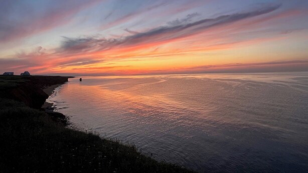 A coastal sunset with a calm sea and a grassy shoreline. - Ocean Front Cottage With Panoramic Water Views- Seconds To Cousin's Shore Beach (Kensington)