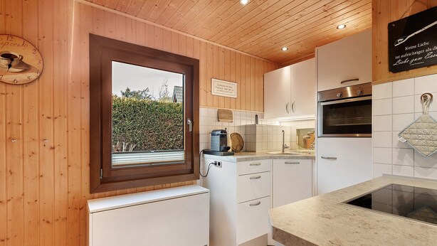 Une cuisine avec des murs en bois, une fenêtre, une horloge et un panneau.