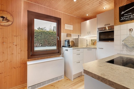 A kitchen with wooden walls, a window, a clock, and a sign.. Holiday Home 'Frenkhausener Ruhepol' with Mountain View, Private Terrace & Wi-Fi