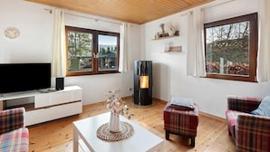 Un salon avec un téléviseur, une cheminée et des meubles recouverts d’un tissu à carreaux.