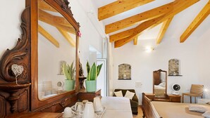 A bedroom with a wooden ceiling, a large mirror, a bed with white bedding, a dresser, a chair, and a small table with a tray of cups and saucers. - 'Peperoncino' Room with Hill View (finale ligure)