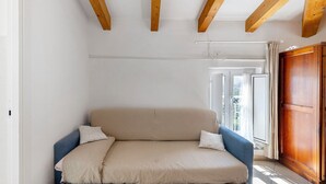 A room with a sofa, wooden beams, a window with curtains, and a door. - Rosmarino Room with Hill View (finale ligure)