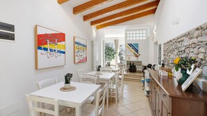 A dining area with white tables and chairs, wooden beams on the ceiling, and artwork on the walls. - Rosmarino Room with Hill View (finale ligure)