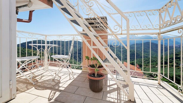 A balcony with white metal railings, a potted plant, and a table and chair set. - Rosmarino Room with Hill View (finale ligure)