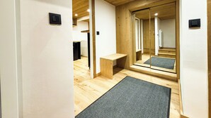 Een modern interieur met houten vloeren, een bankje, een spiegel en een deur naar een andere kamer.