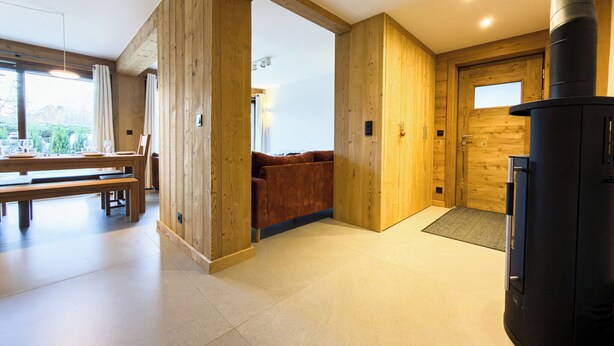 Een modern interieur met houten wanden, een eethoek, een bank en een zwart fornuis.