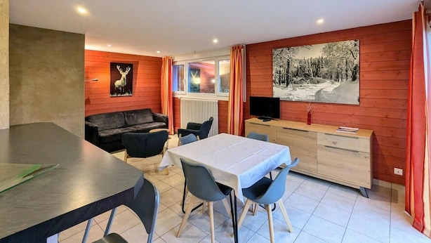 Ein modernes Wohnzimmer mit einer Couch, einem Esstisch, Stühlen und einem Fernseher.