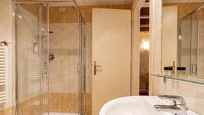 Une salle de bain moderne avec une douche à parois de verre, un lavabo blanc et une étagère en verre au-dessus du lavabo.