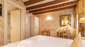 Une chambre d’hôtel avec un lit, un bureau, une chaise et une armoire.