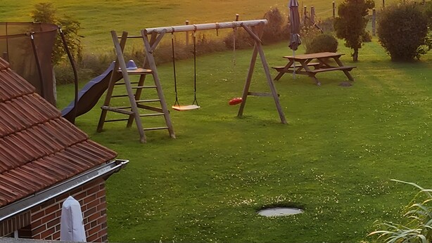 Un atardecer sobre un campo cubierto de césped, con un columpio y una mesa de picnic.