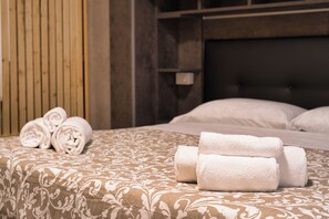 A neatly made bed with rolled towels and a patterned bedspread. - Cozy mountain escape near Como lake (Ballabio)