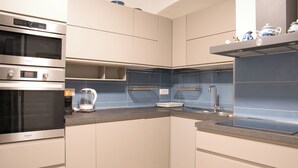 A modern kitchen with stainless steel appliances, a built-in oven, a coffee maker, and a sink. - Cozy mountain escape near Como lake (Ballabio)