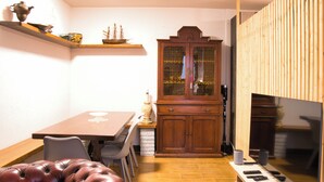 A dining area with a wooden table, chairs, a cushioned bench, a cabinet with glass doors, and a television. - Cozy mountain escape near Como lake (Ballabio)