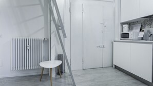 Una cocina moderna con armarios blancos, un microondas y una pequeña mesa de comedor.