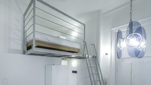 Una litera con escalera, una puerta con lámpara y una lámpara fijada a la pared.