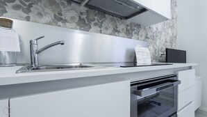 Una cocina moderna con un lavamanos de acero inoxidable, horno empotrado y microondas.