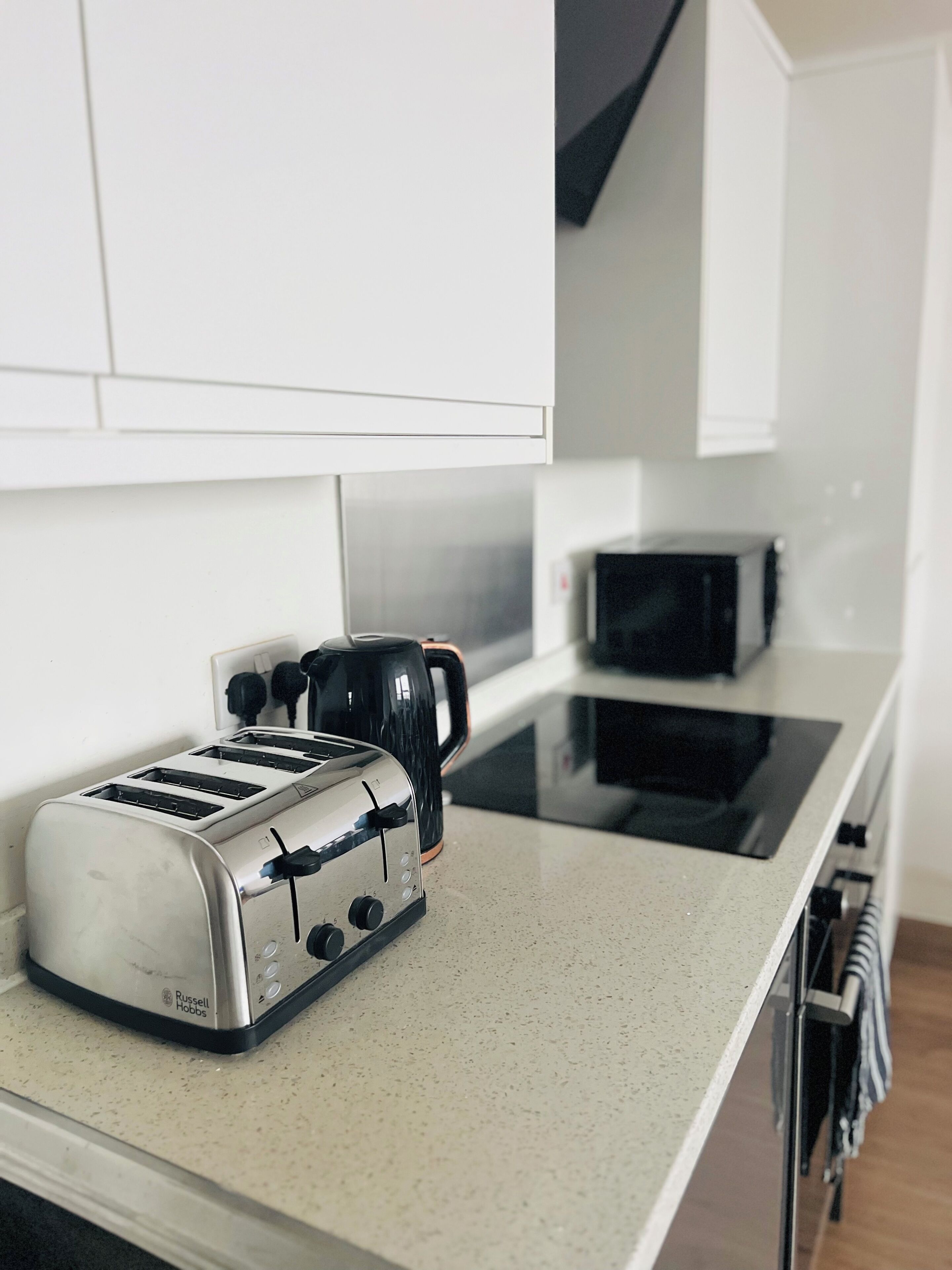 A kitchen with a toaster, a coffee maker, and a microwave on a countertop.