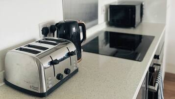 A kitchen with a toaster, a coffee maker, and a microwave on a countertop.