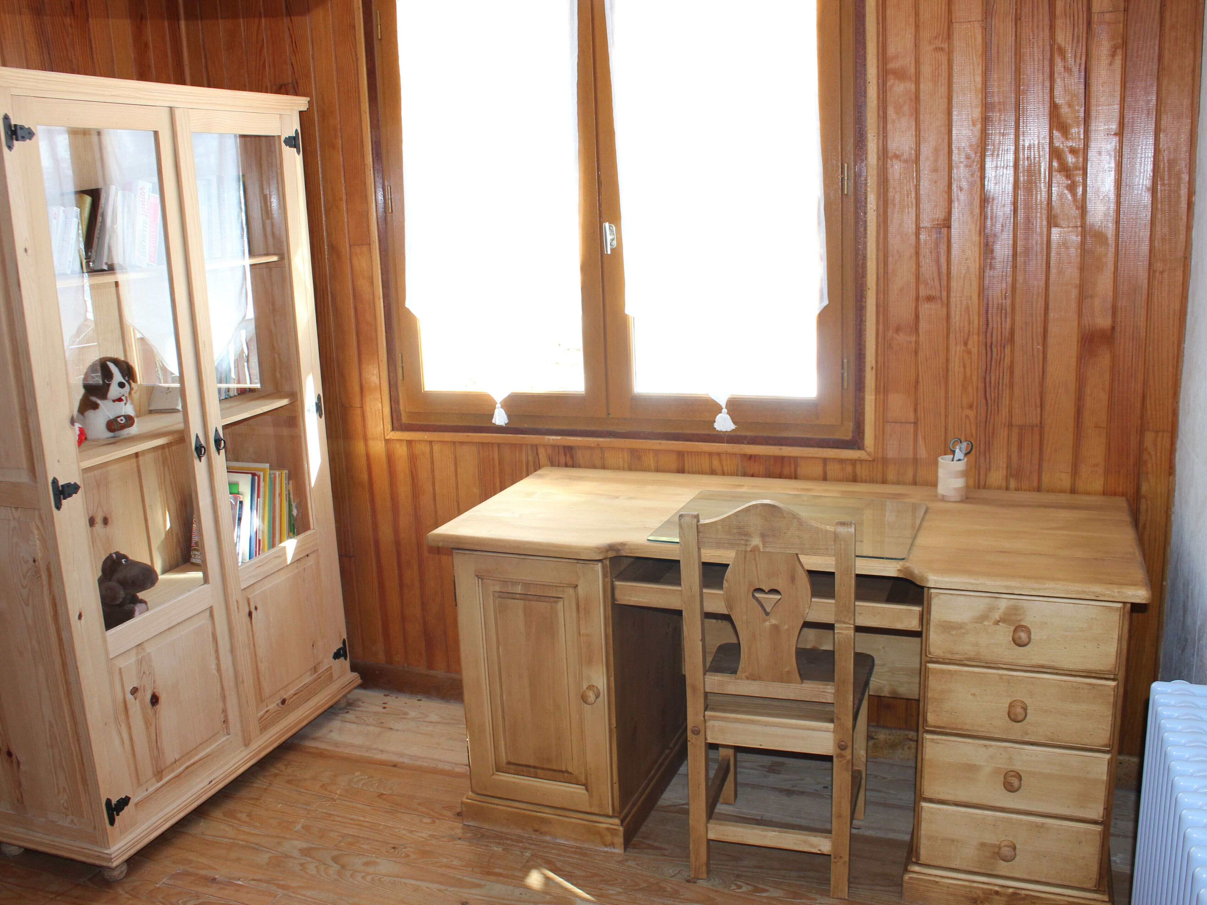 Una stanza in legno con una scrivania, una sedia e un armadietto con vetrate.