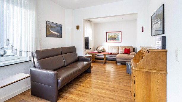 A modern living room with a leather sofa, a wooden coffee table, and a wooden cabinet. - Knappstein Holiday Home with 4 Bedrooms, Garden, and Wi-Fi (Möhnesee)