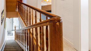A wooden staircase with a handrail, leading to a bedroom with a bed and a nightstand. - Knappstein Holiday Home with 4 Bedrooms, Garden, and Wi-Fi (Möhnesee)