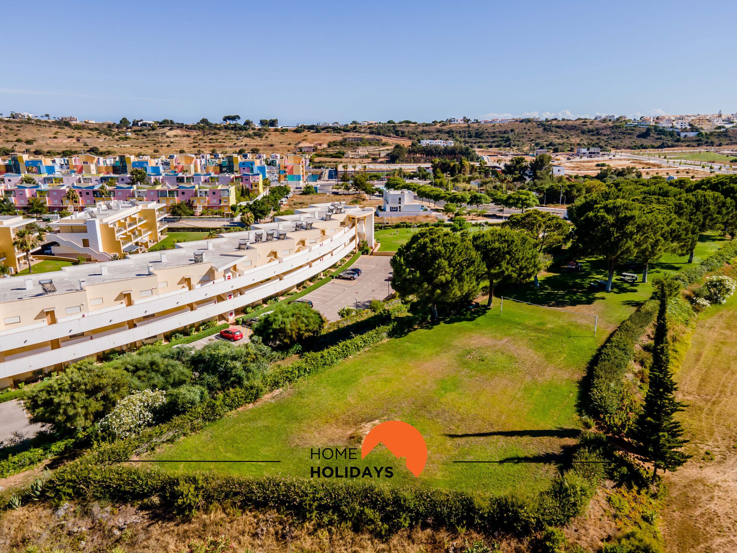 Un quartiere residenziale con case colorate, un parcheggio e aree verdi.