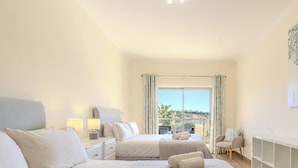 A bedroom with two beds, a balcony, and a view of the landscape. - #323 Marina Apartment | Pool & Views (Albufeira)