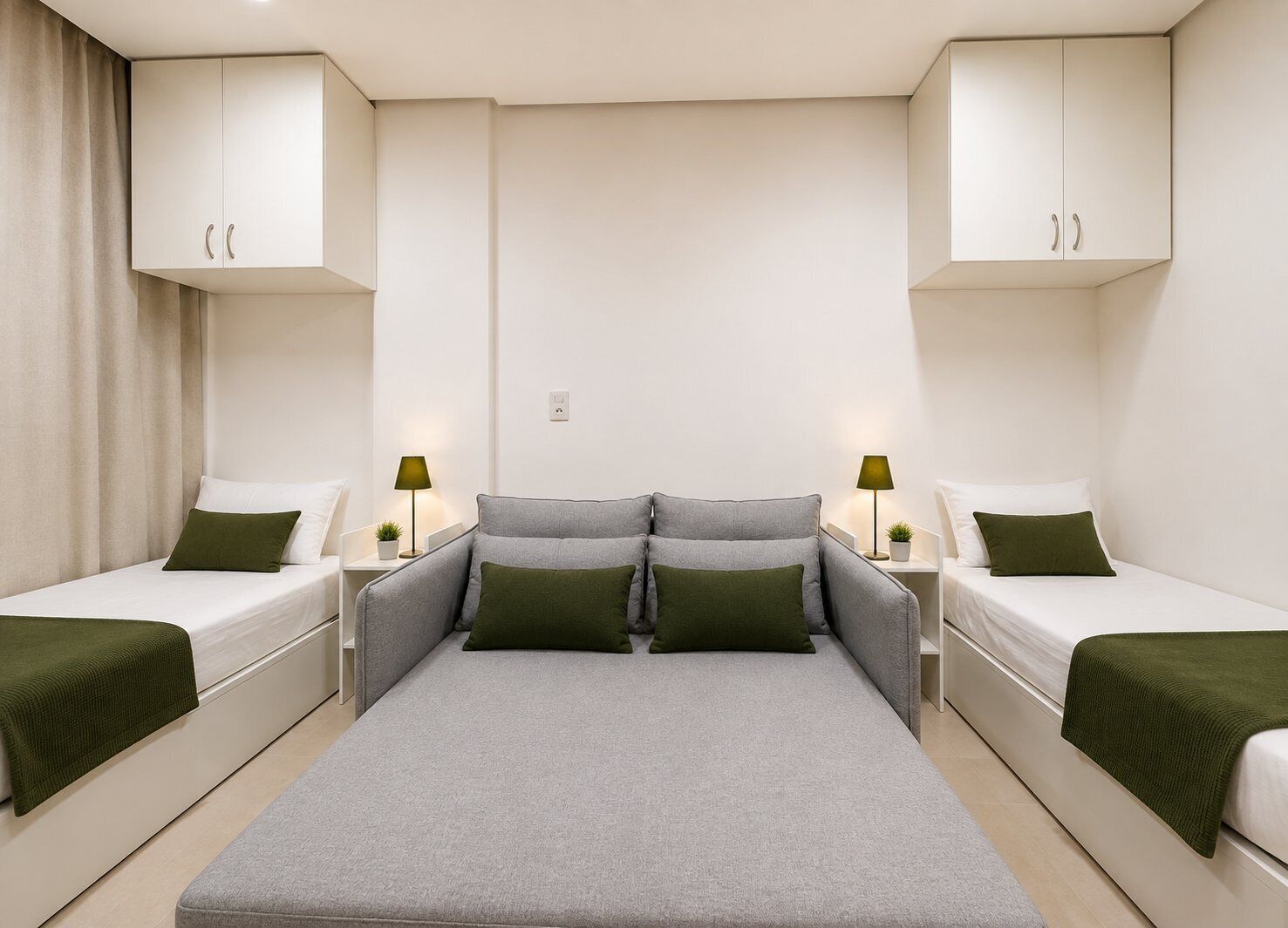 Hotelkamer met een centraal bed, geflankeerd door twee eenpersoonsbedden, een slaapbank en een kleine tafel met lamp.