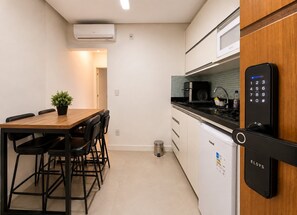 A compact kitchen with a dining area, a microwave, a sink, and a refrigerator. - Apartment Posto 5, close to the beach (Rio de Janeiro)