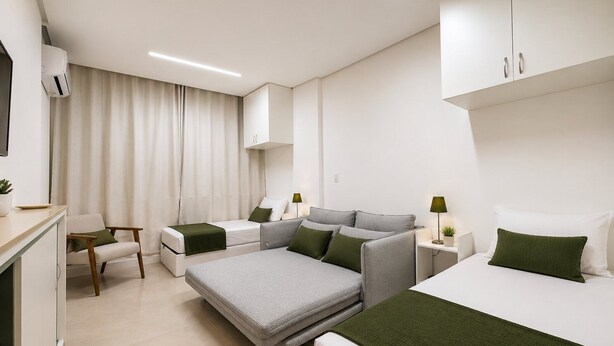 Une chambre d’hôtel moderne équipée d’un canapé-lit, d’un lit simple, d’un bureau et d’une chaise.