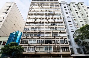 A multi-story building with a grid-like facade, air conditioning units, and a mix of window styles. - Apartment Posto 5, close to the beach (Rio de Janeiro)