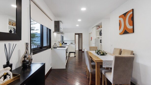 A modern kitchen with a dining area, a large window, and a decorative wall piece. - Casa São Domingos Lousada – Conforto e Vista Deslumbrante para a Vossa Família (Lousada)