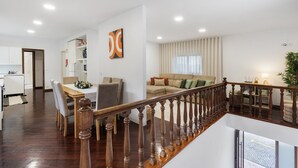A spacious living area with a wooden staircase, a dining area, and a kitchen. - Casa São Domingos Lousada – Conforto e Vista Deslumbrante para a Vossa Família (Lousada)