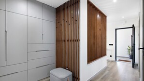 Un intérieur moderne avec une armoire grise, une cloison en lattes de bois et un pouf gris.