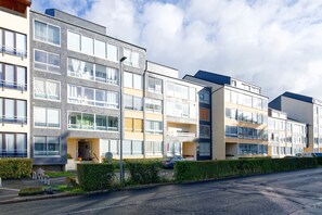 Moderni kerrostalo, jossa on useita kerroksia, suuret ikkunat ja parvekkeet.