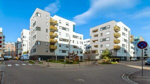 En modern hyresfastighet med balkonger, en skylt som förbjuder parkering och en klarblå himmel.