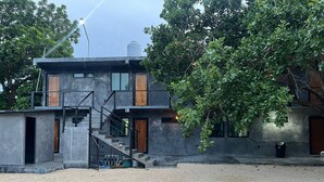 Uma casa moderna de dois andares com fachada de concreto, escada de madeira e pequena área externa com cascalho.
