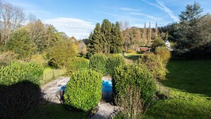 Un quartier résidentiel doté d’une pelouse bien entretenue, d’un chemin menant à une structure bleue, ainsi que de diverses espèces d’arbres et d’arbustes.