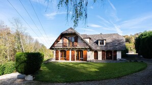 Une maison à deux étages dotée d’un balcon, d’une allée en gravier et d’une pelouse bien entretenue.