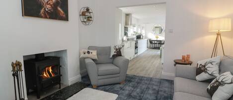 A living room with a fireplace, grey sofa, and a plaid rug.