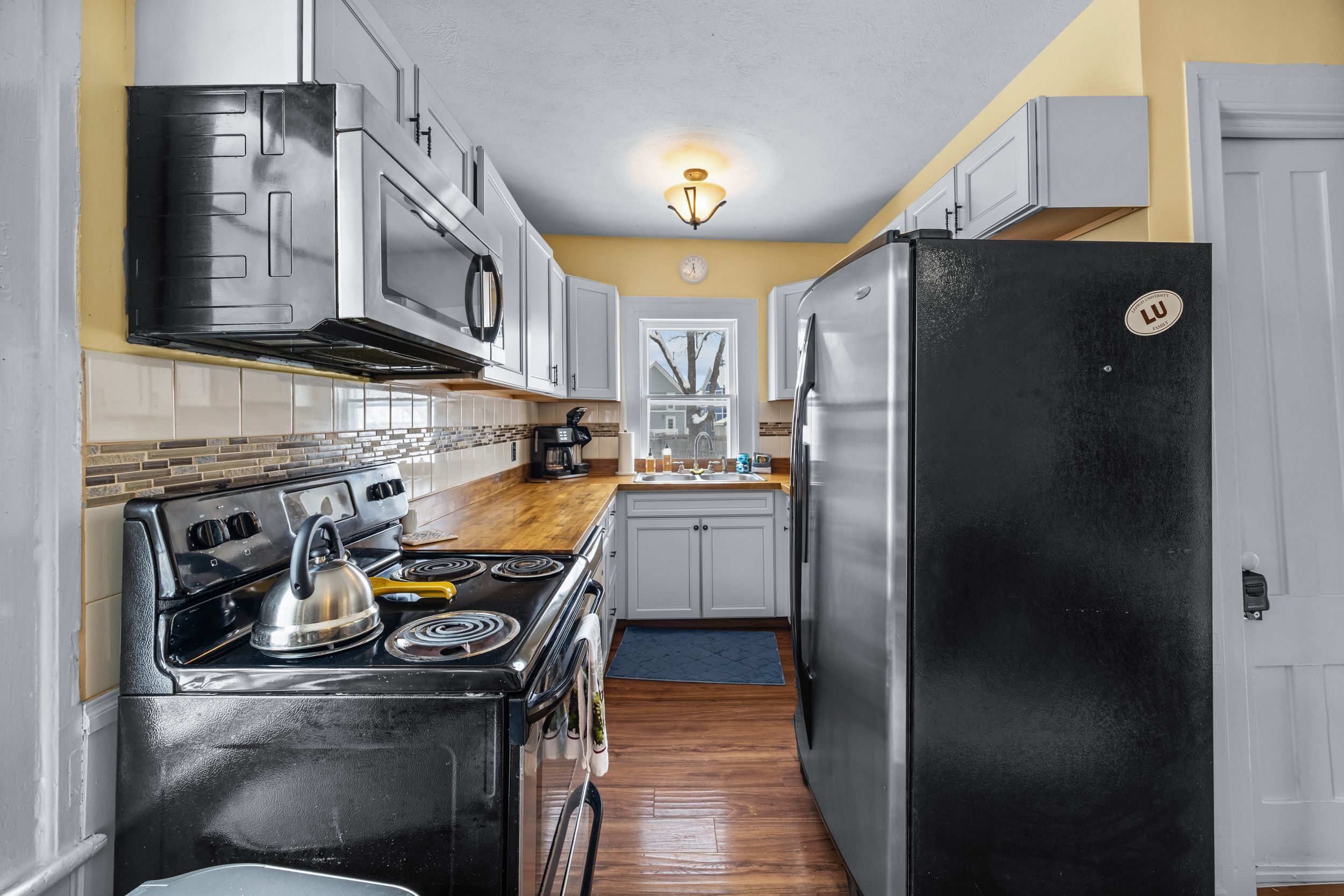 A compact kitchen with stainless steel appliances, a microwave, and a stove.