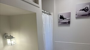 A bathroom with a white sink, toilet, and shower curtain. There are two wall-mounted pictures, one of a bathtub and one of a person in a bathtub. - The Resorts World Retreat Spacious 4-bedroom house in beautiful Monticello (Monticello)